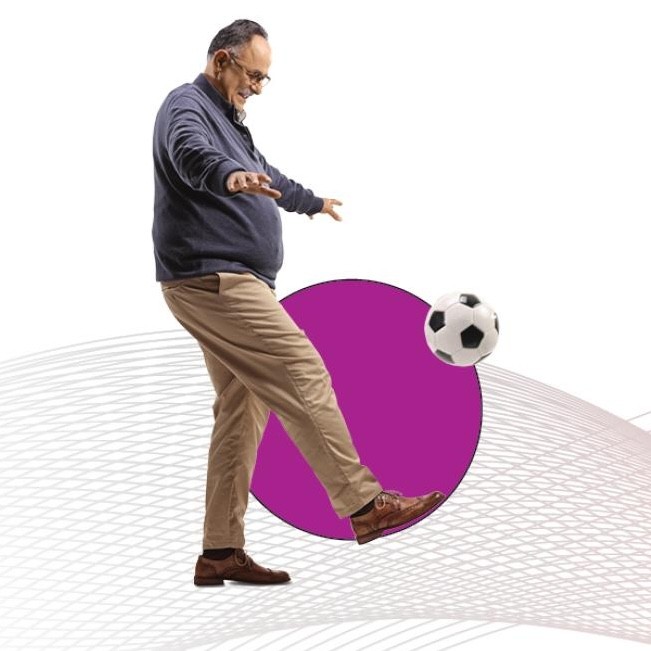 An older person kicking a soccer ball.